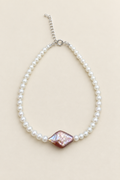 Brilliant white pearl bracelet with purple-pink centre pearl on warm ivory background