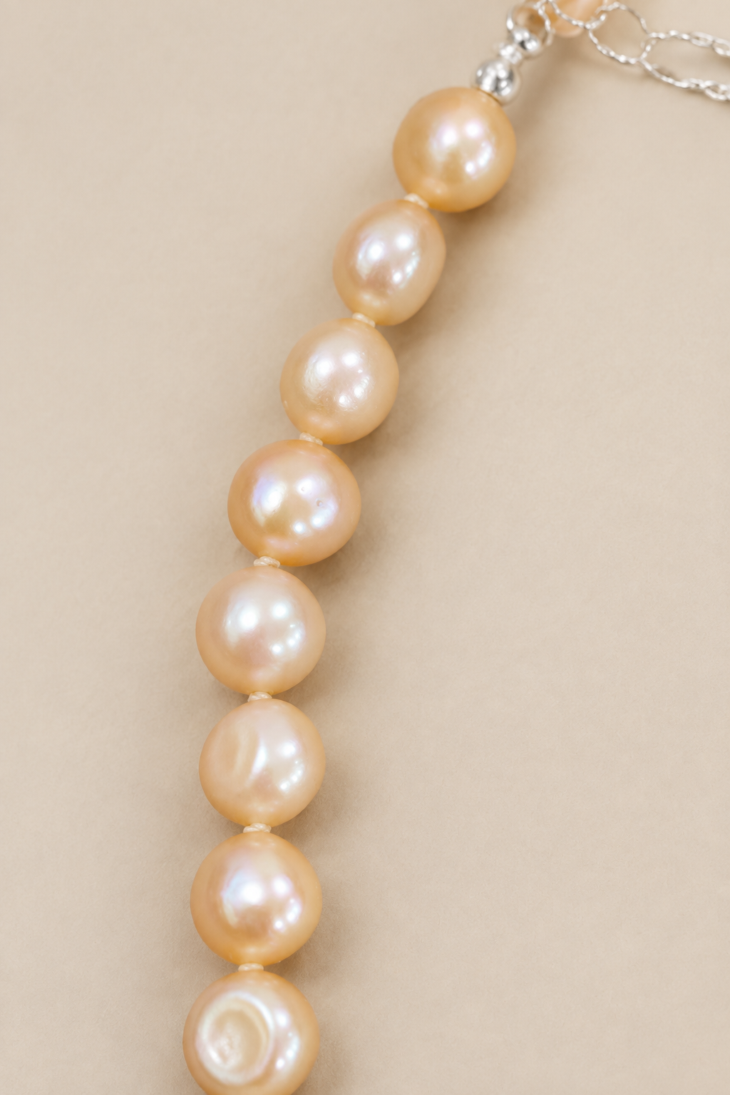 Close-up of Baby Bubbles golden-peach pearls on warm beige background