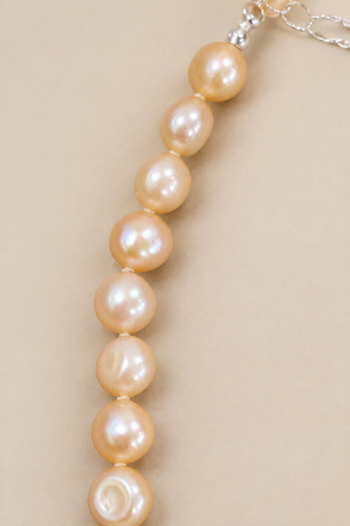 Close-up of Baby Bubbles golden-peach pearls on warm beige background