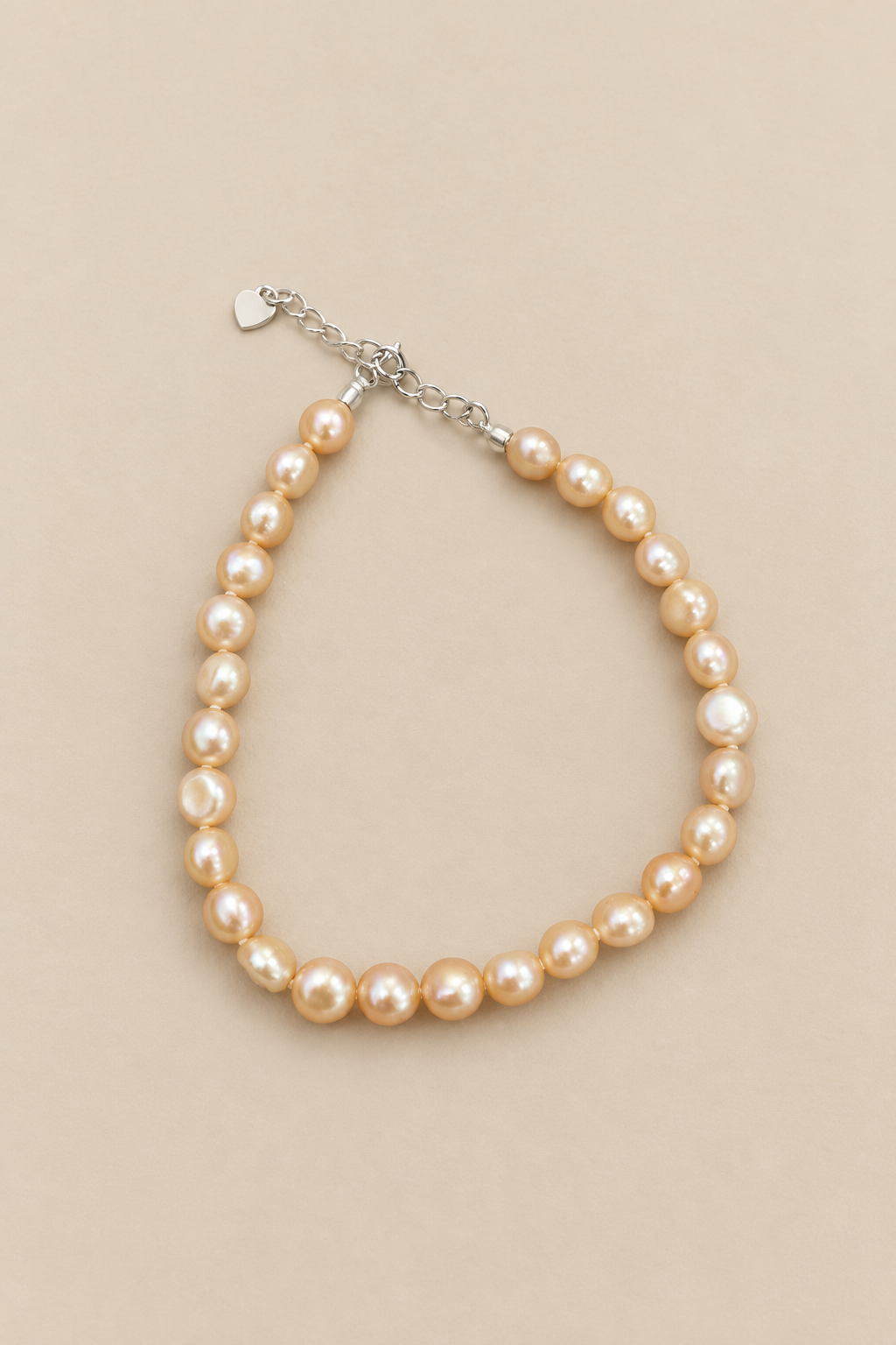 Baby Bubbles golden-peach pearl bracelet on warm beige background