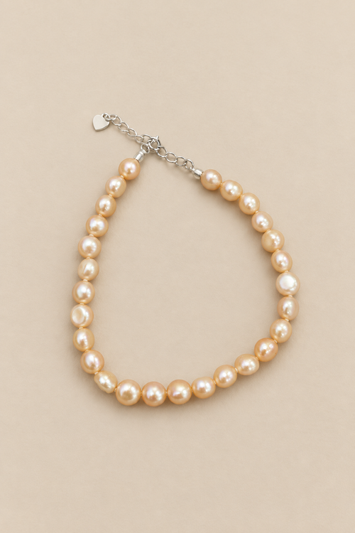 Baby Bubbles golden-peach pearl bracelet on warm beige background