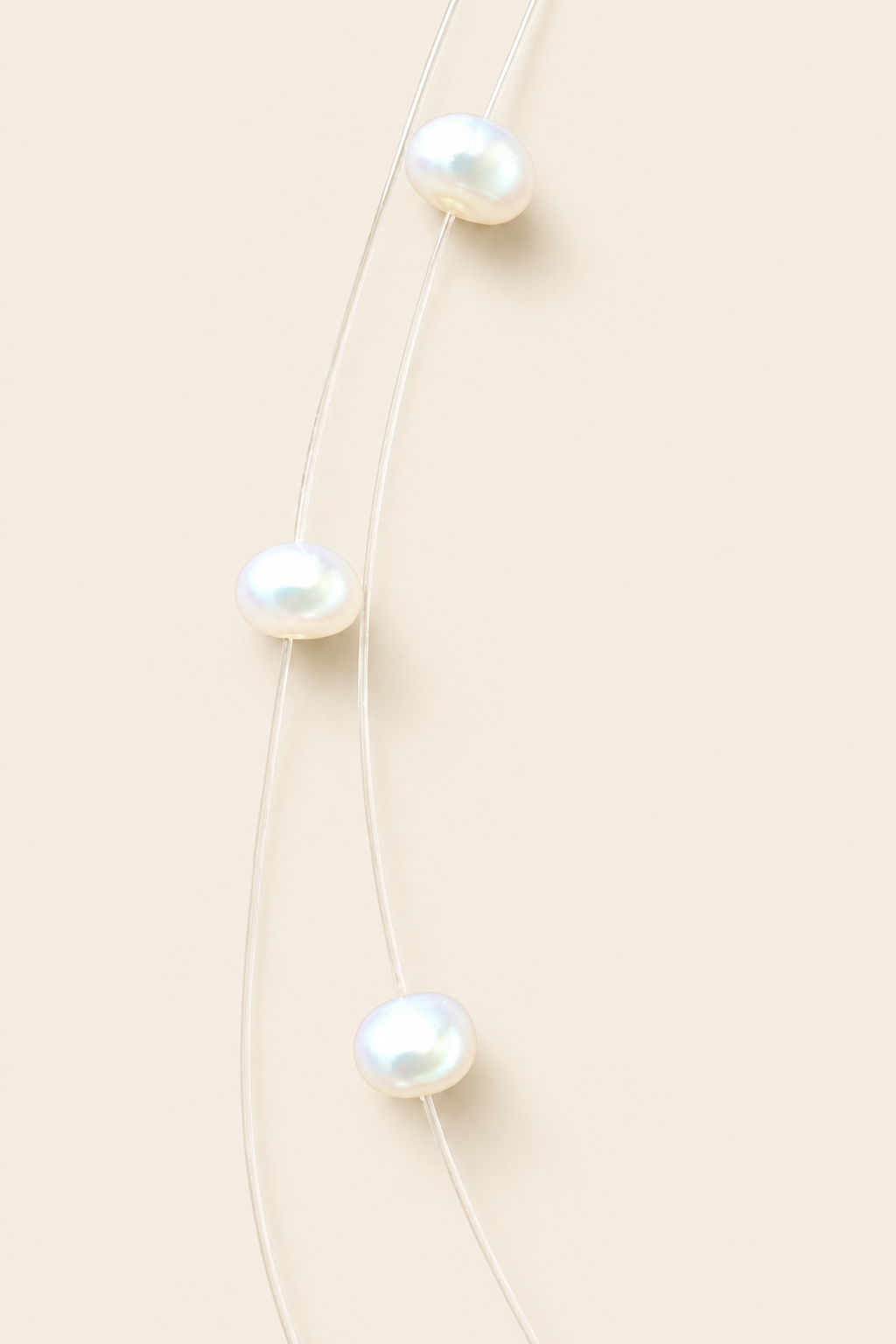 Close-up of white freshwater pearls on fine strand, light beige background