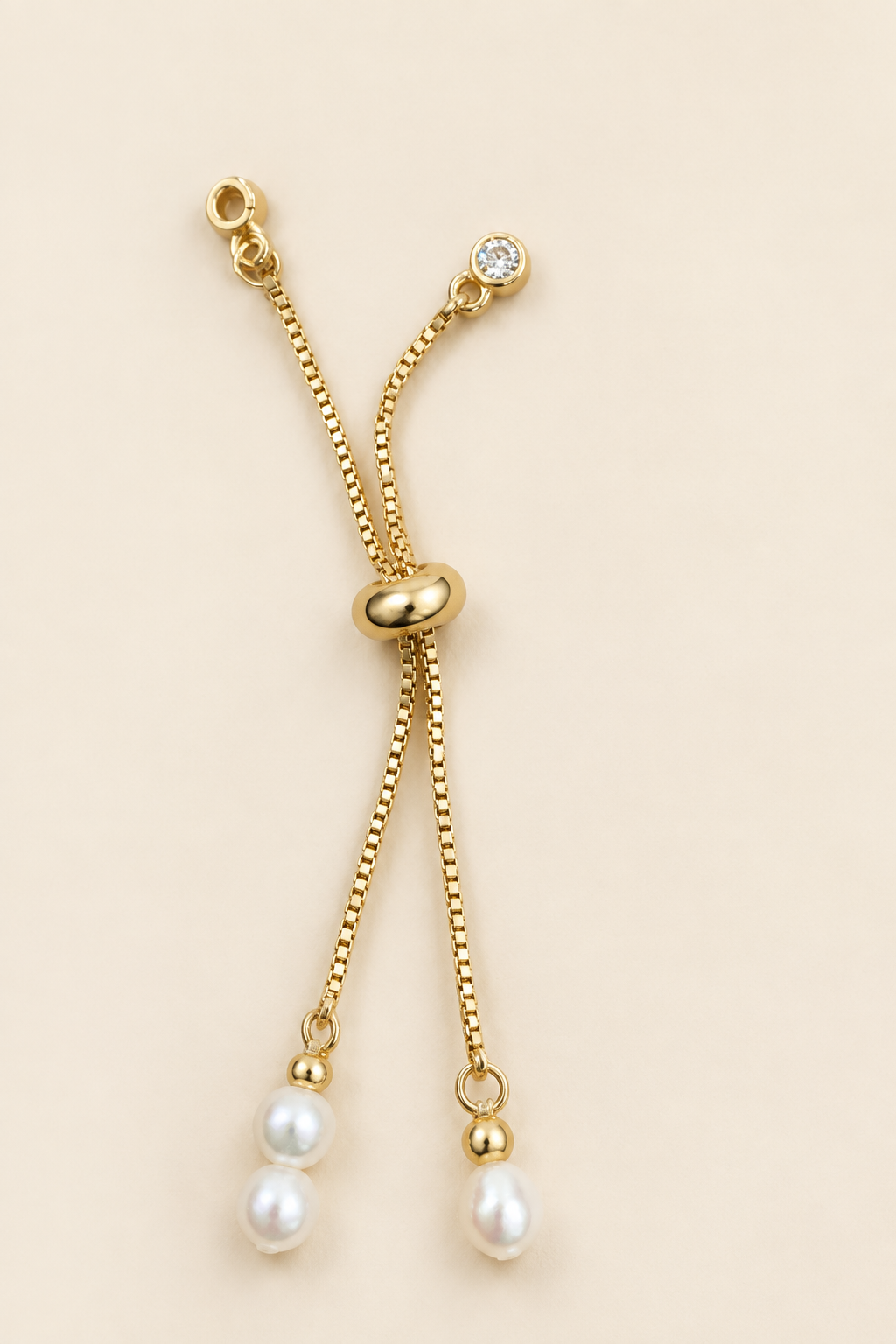 Close-up of adjustable gold-plated back chain on warm ivory background